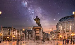 Skopje atrakcje nocą: pomnik Wojownika na koniu, fontanny i Droga Mleczna nad miastem.