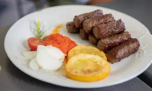 Cevapi, klasyka kuchni słoweńskiej, podane z ajvarem, cebulą i pomidorem.