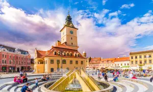 Rynek w Braszowie w Rumunii, z ratuszem i fontanną, tętni życiem.