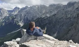 Mężczyzna odpoczywa na skale, podziwiając majestatyczne, skaliste góry przeklęte.