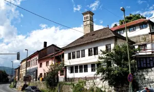 Kolorowe kamienice i wieża zegarowa w Travniku, Bośnia, pod błękitnym niebem z chmurami.