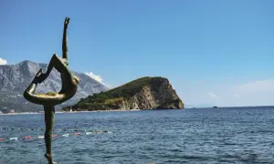 Posąg tancerki na tle gór i morza, idealne miejsce na balkan trip.