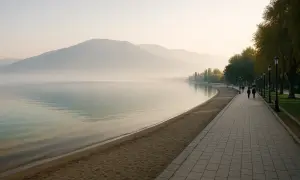 Spokojny poranek nad jeziorem w Pogradec, Albania. Mgła otula góry, a spacerowicze cieszą się spokojem promenady.