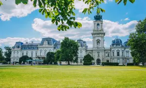 Pałac Festetics w Keszthely, jedna z głównych atrakcji, otoczony zielonym parkiem i błękitnym niebem.