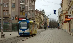 Tram w centrum Osijek, Chorwacja. W tle kamienice i sklepowe witryny.