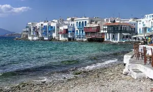 Malownicze Mykonos: białe domy z niebieskimi okiennicami nad turkusowym morzem. Warto sprawdzić mykonos ceny przed podróżą.