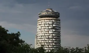 Okrągły wieżowiec z balkonami, przypominający grzyb, to jedna z **kiszyńiów atrakcji**. W tle ciemne chmury.