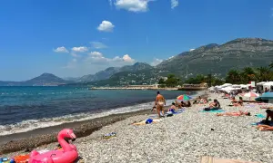 Sutomore atrakcje: plaża z kamienistym brzegiem, turkusowe morze i góry w tle. Różowy flaming na piasku zaprasza do relaksu.