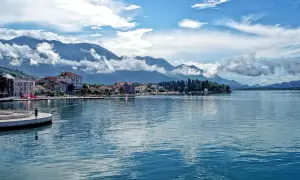 Widok na spokojną kotor zatoka z górami w tle i miasteczkiem nad brzegiem.