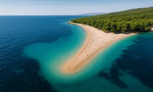 Widok z lotu ptaka na piaszczysty cypel otoczony turkusową wodą. Rajskie plaże z zielonym lasem w tle.