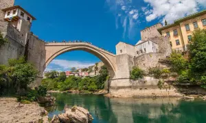 Mostar, Bośnia i Hercegowina. Słynny Stary Most nad rzeką Neretwą. Turyści podziwiają widoki, a ceny pamiątek są przystępne.
