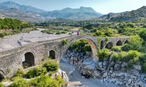 Kamienna, zabytkowa konstrukcja w Szkodrze, Albania, z kobietą w fioletowej sukni na szczycie.