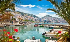 Albania, gdzie na wakacje? Widok na port z łodziami i kolorowe budynki na wzgórzu. Idealne miejsce na wypoczynek.