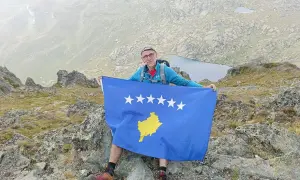 Mężczyzna z flagą Kosowa na szczycie góry. Niesamowite kosowo wakacje w górach.