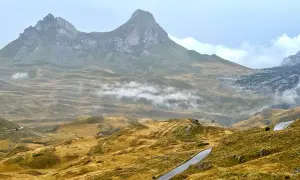 Górzyste krajobrazy Durmitor National Park, z krętymi drogami i mgłą unoszącą się nad złotymi wzgórzami.