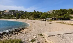 Plaża w Kupari, Chorwacja, z turkusową wodą, kamienistym brzegiem i hotelami w tle.