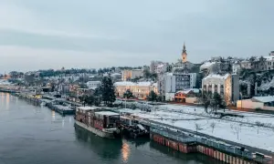 Zimowy Belgrad nad Dunajem, z ośnieżonymi budynkami i statkami. Czy Serbia jest bezpieczna? Widok sugeruje spokojne miasto.