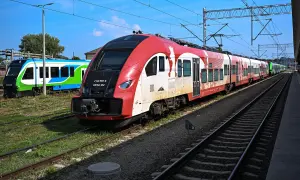Czerwono-biały pociąg do bukaresztu stoi na torach obok zielono-niebieskiego składu.