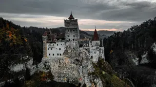 Mroczny, majestatyczny Bran Castle wznosi się na skale, otoczony gęstym lasem.