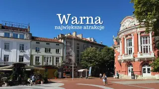 Warna, miasto pełne życia i kolorów. Na placu z czerwonej cegły widać ludzi spacerujących obok zabytkowych budynków, w tym teatru.