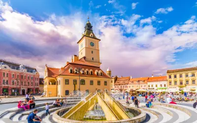 Rynek w Braszowie w Rumunii, z ratuszem i fontanną, tętni życiem.