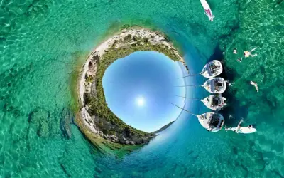Rajskie **peloponez plaże** z krystalicznie czystą wodą, żaglówkami i ludźmi kąpiącymi się w słońcu.