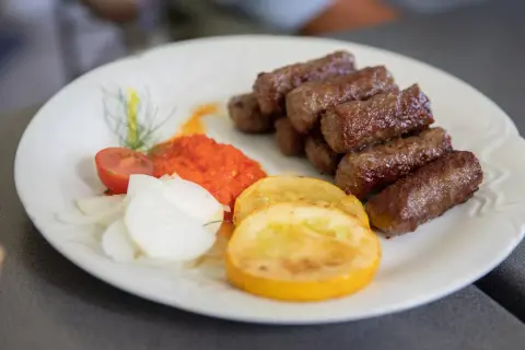 Cevapi, klasyka kuchni słoweńskiej, podane z ajvarem, cebulą i pomidorem.