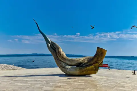 Monumentalna rzeźba na promenadzie w Durrës, plaża w tle, błękitne niebo i morze.