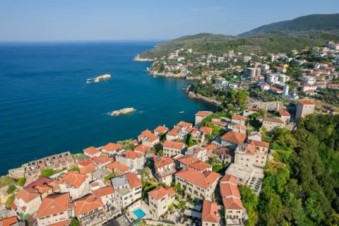 Widok na miasto Ulcinj z lotu ptaka. Czerwone dachy, kamienne budynki i błękitne morze tworzą malowniczy krajobraz. To miejsce pełne atrakcji.