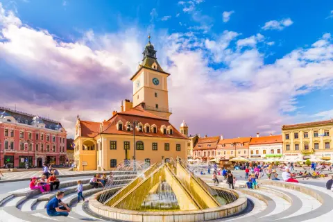 Rynek w Braszowie w Rumunii, z ratuszem i fontanną, tętni życiem.