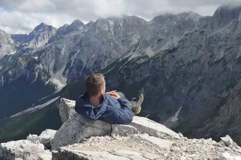 Mężczyzna odpoczywa na skale, podziwiając majestatyczne, skaliste góry przeklęte.