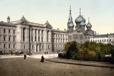 Dawne budynki i cerkiew na brukowanym placu, świadczące o tym, gdzie leży Odessa. Ludzie spacerują, a powozy stoją.
