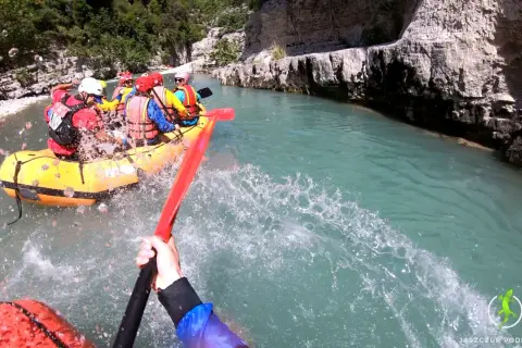 Rafting w malowniczym kanionie w Albanii. Grupa turystów w żółtej łodzi pokonuje rwący nurt rzeki, otoczeni skalnymi ścianami.