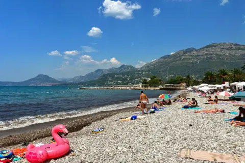 Sutomore atrakcje: plaża z kamienistym brzegiem, turkusowe morze i góry w tle. Różowy flaming na piasku zaprasza do relaksu.