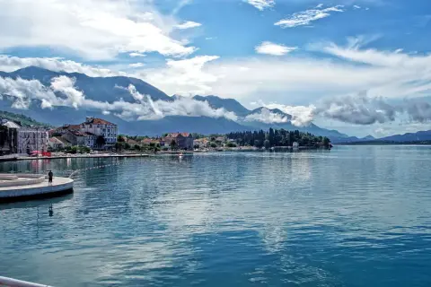 Widok na spokojną kotor zatoka z górami w tle i miasteczkiem nad brzegiem.