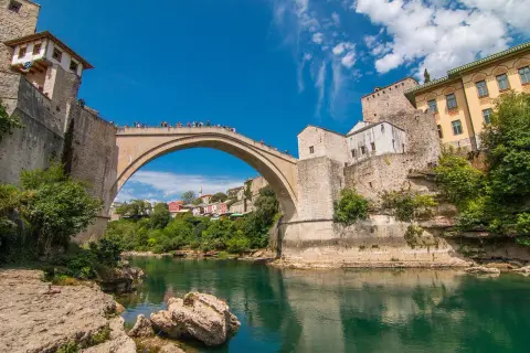 Mostar, Bośnia i Hercegowina. Słynny Stary Most nad rzeką Neretwą. Turyści podziwiają widoki, a ceny pamiątek są przystępne.