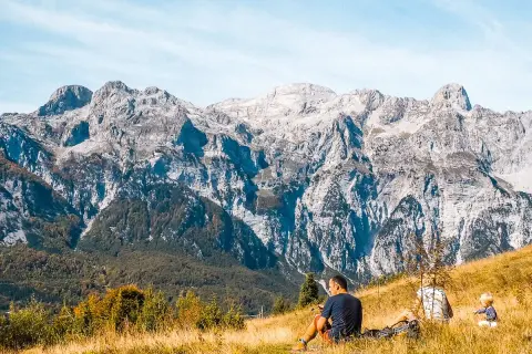 Rodzina odpoczywa na trawiastym zboczu, podziwiając majestatyczne albania góry.