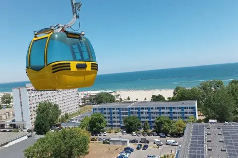 Żółta kolejka linowa nad kurortem z widokiem na piękne **konstanca plaże** i błękitne morze.