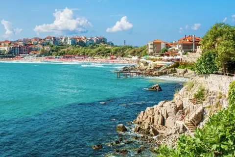 Słoneczne bułgarskie miasta turystyczne nad turkusowym morzem. Widok na plażę, klify i zabudowania.