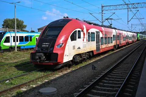 Czerwono-biały pociąg do bukaresztu stoi na torach obok zielono-niebieskiego składu.