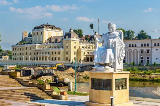 Pomnik w centrum Skopje, stolicy Macedonii Północnej, na tle rzeki i budynków.
