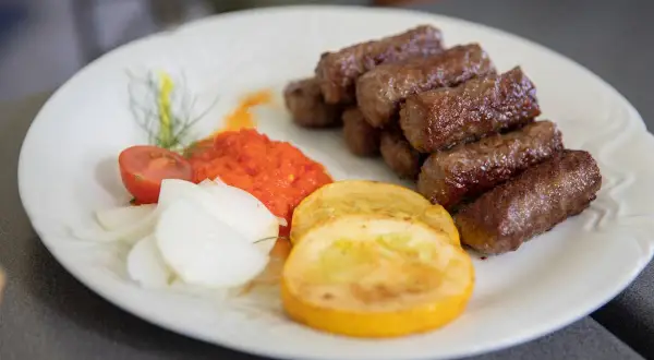 Cevapi, klasyka kuchni słoweńskiej, podane z ajvarem, cebulą i pomidorem.