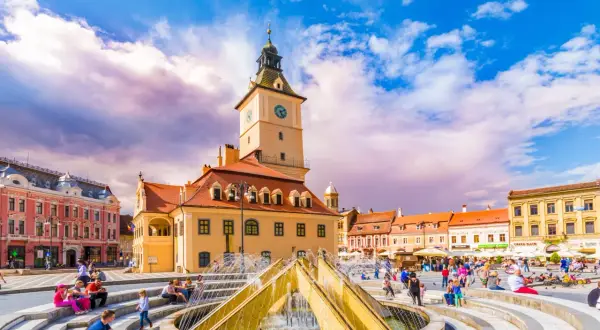 Rynek w Braszowie w Rumunii, z ratuszem i fontanną, tętni życiem.