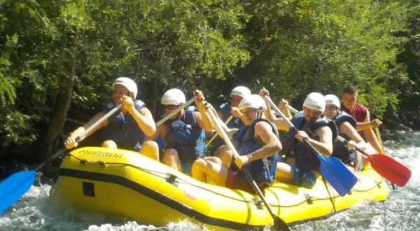 Grupa ludzi na raftingu na rzece Cetina w Chorwacji, wiosłując przez bystrza.