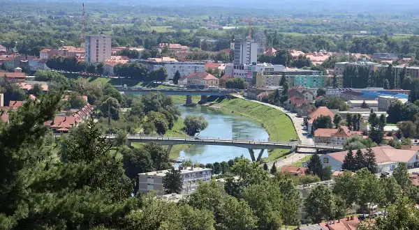 Widok na miasto Karlovac w Chorwacji z rzeką przecinającą krajobraz i mostami łączącymi brzegi.