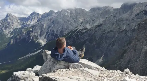 Mężczyzna odpoczywa na skale, podziwiając majestatyczne, skaliste góry przeklęte.