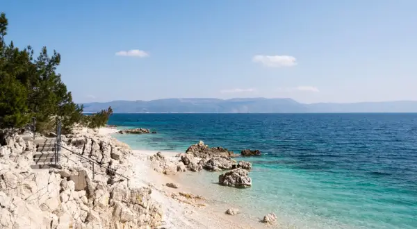 Kamienista plaża z turkusową wodą i schodami prowadzącymi do morza. Idealne miejsce na odkrywanie uroków Chorwacji, Istria atrakcje.