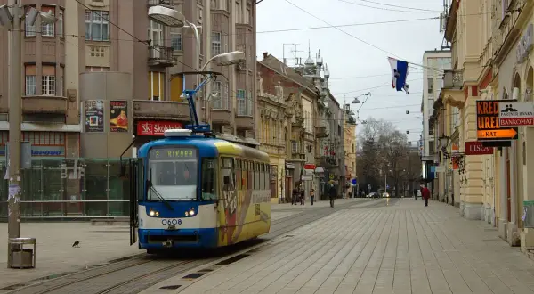 Tram w centrum Osijek, Chorwacja. W tle kamienice i sklepowe witryny.