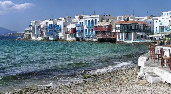 Malownicze Mykonos: białe domy z niebieskimi okiennicami nad turkusowym morzem. Warto sprawdzić mykonos ceny przed podróżą.