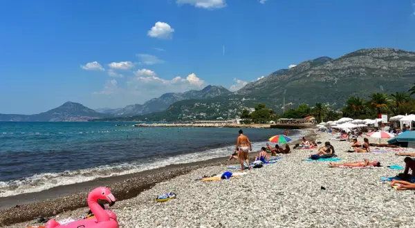 Sutomore atrakcje: plaża z kamienistym brzegiem, turkusowe morze i góry w tle. Różowy flaming na piasku zaprasza do relaksu.